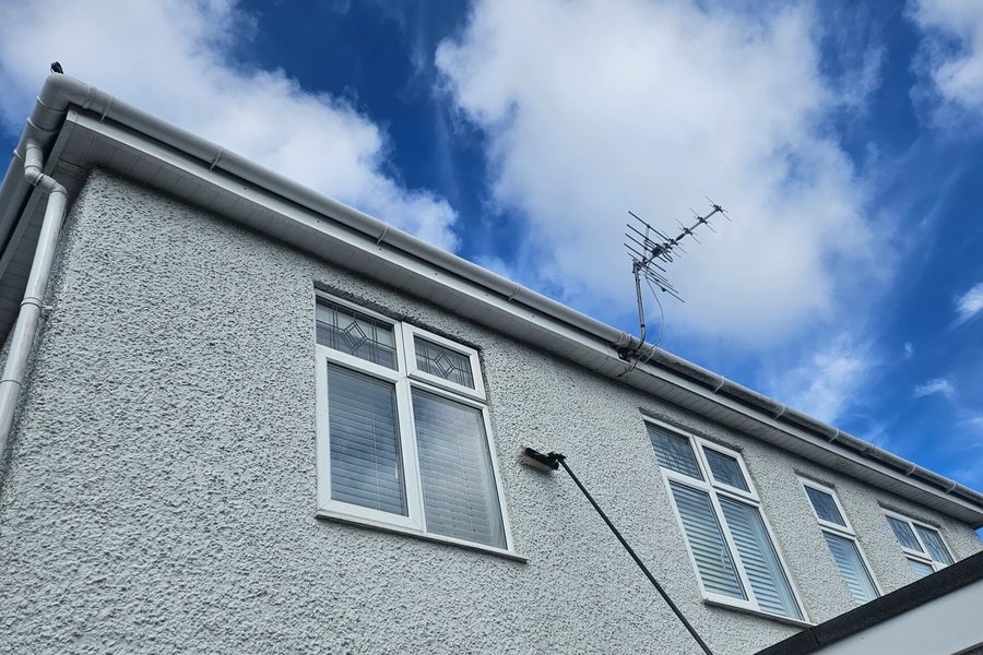 A water-fed pole reaching upstairs windows on a rendered house.